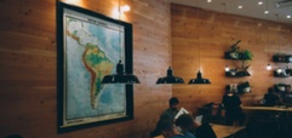 Study room with wooden walls, low hanging lights, students at a long table and a large map of South America on the wall
