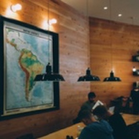 Study room with wooden walls, low hanging lights, students at a long table and a large map of South America on the wall